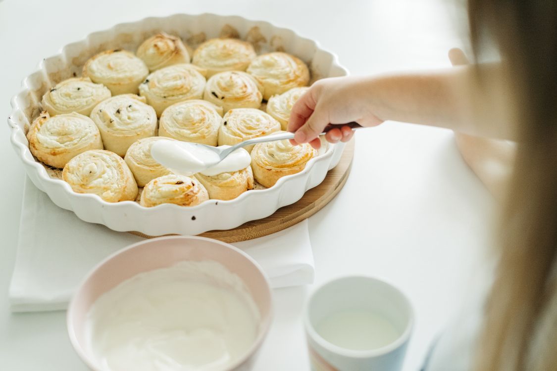 Barn som brer glasyr på nybakade kanelbullar
