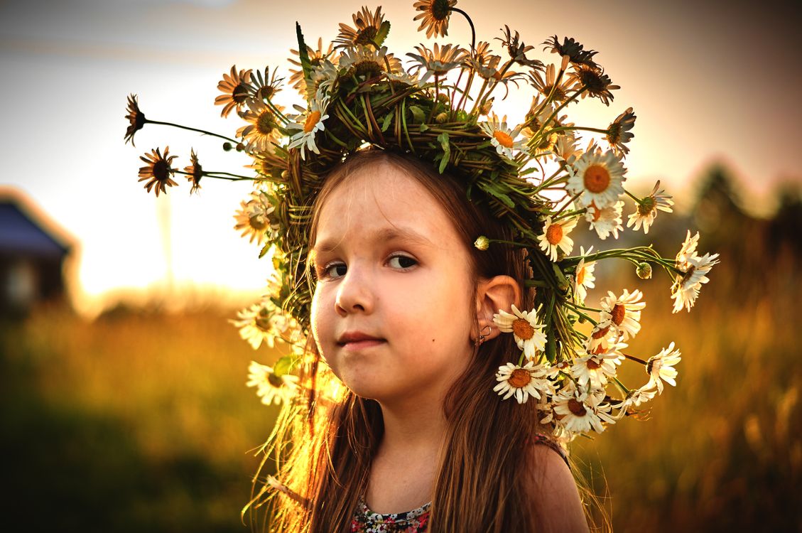 Två flickor med blomsterkransar i en solig sommaräng